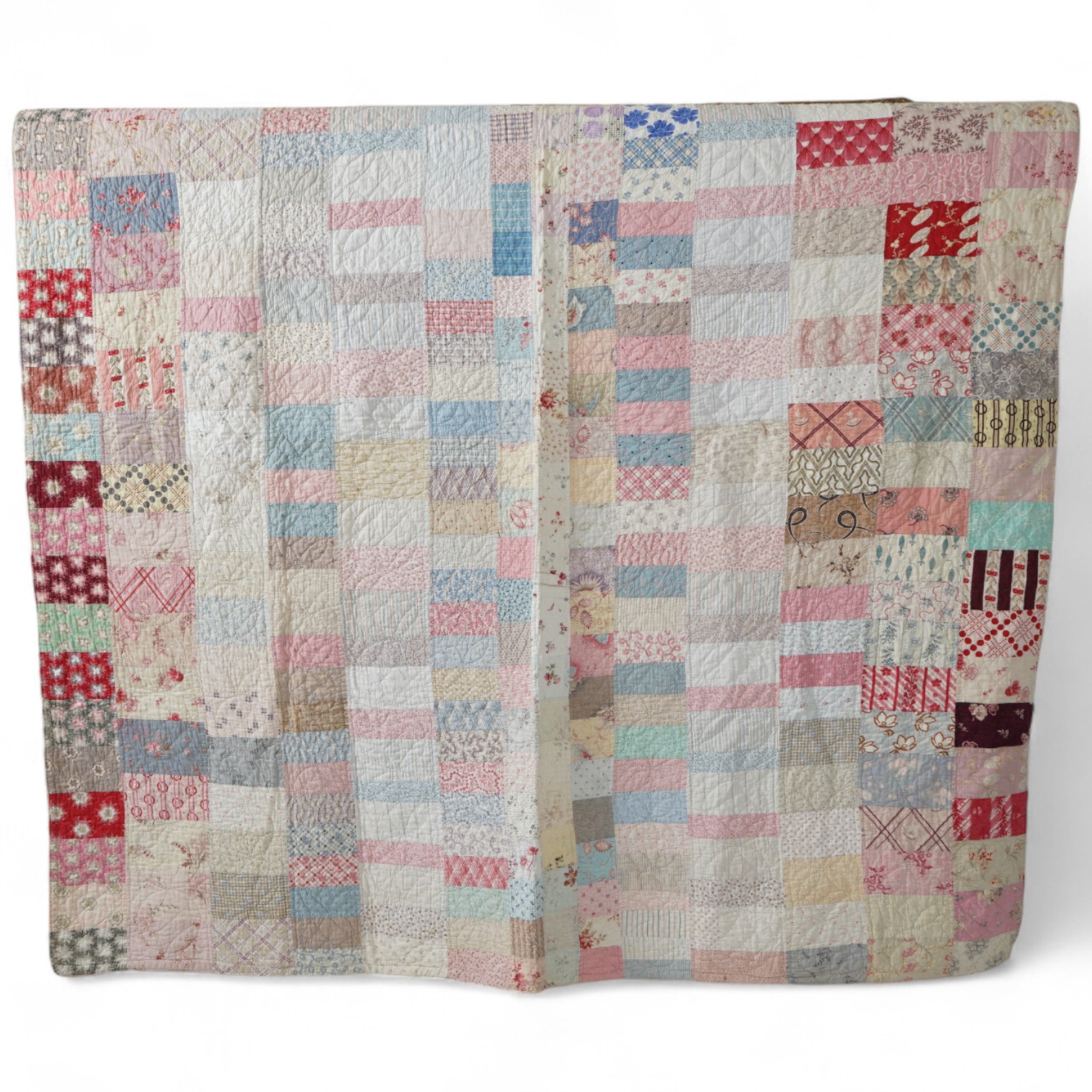 A late 19th early 20th century English cotton ‘scrap bag’ quilt., Made from a large variety of fashionable printed floral, striped and checked cottons of the day, cut into different sized rectangles and squares. Backed w